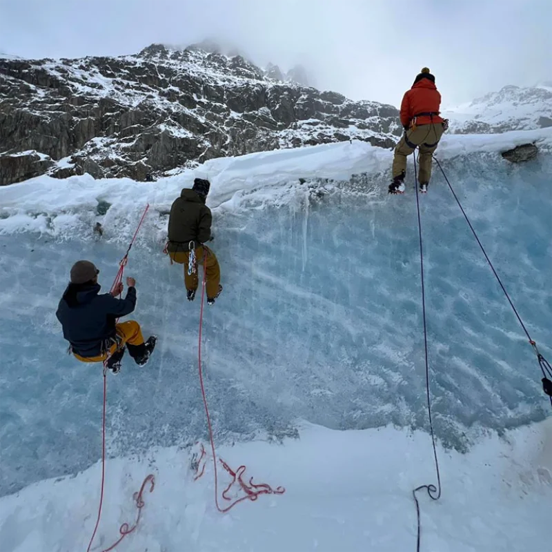 Team practicing fall arrest and self-rescue methods on a training glacier