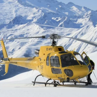 Helicopter dropping skiers on a remote alpine summit