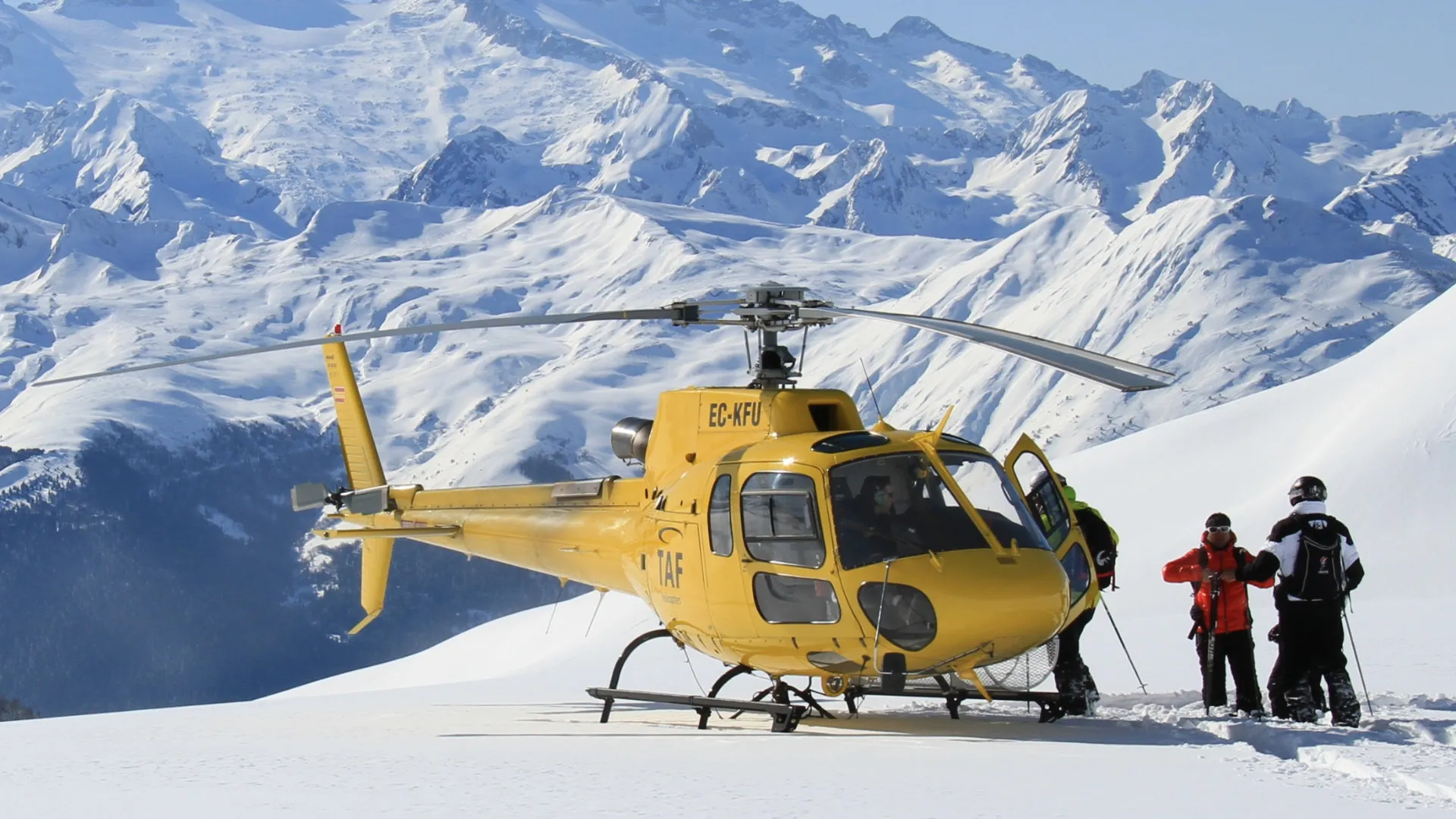 Helicopter dropping skiers on a remote alpine summit