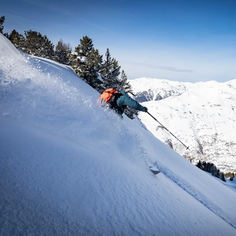 Skier carving fresh tracks on a remote heliski slope
