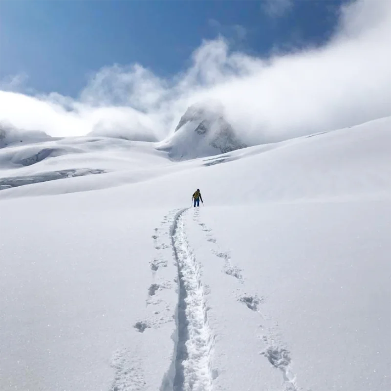 Skiers transitioning to descent on a high alpine ridge