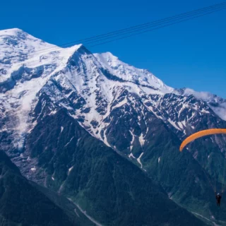Colorful paraglider wing against a clear alpine sky