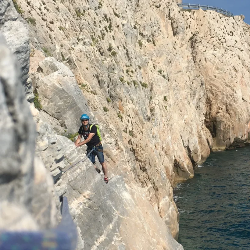 Beginner learning climbing skills on a sunny rock face